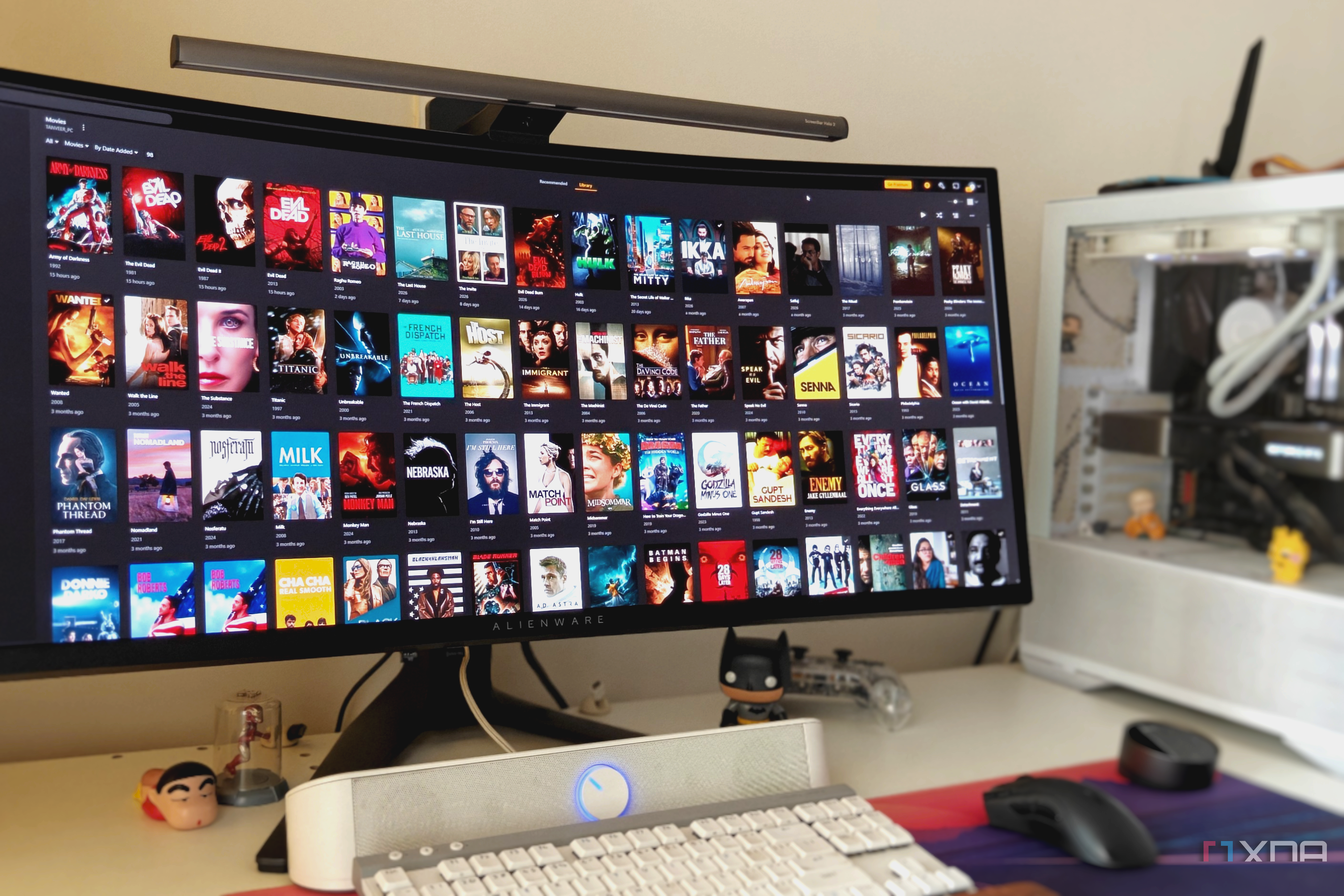 Plex library in a browser window on an ultrawide monitor next to a white PC