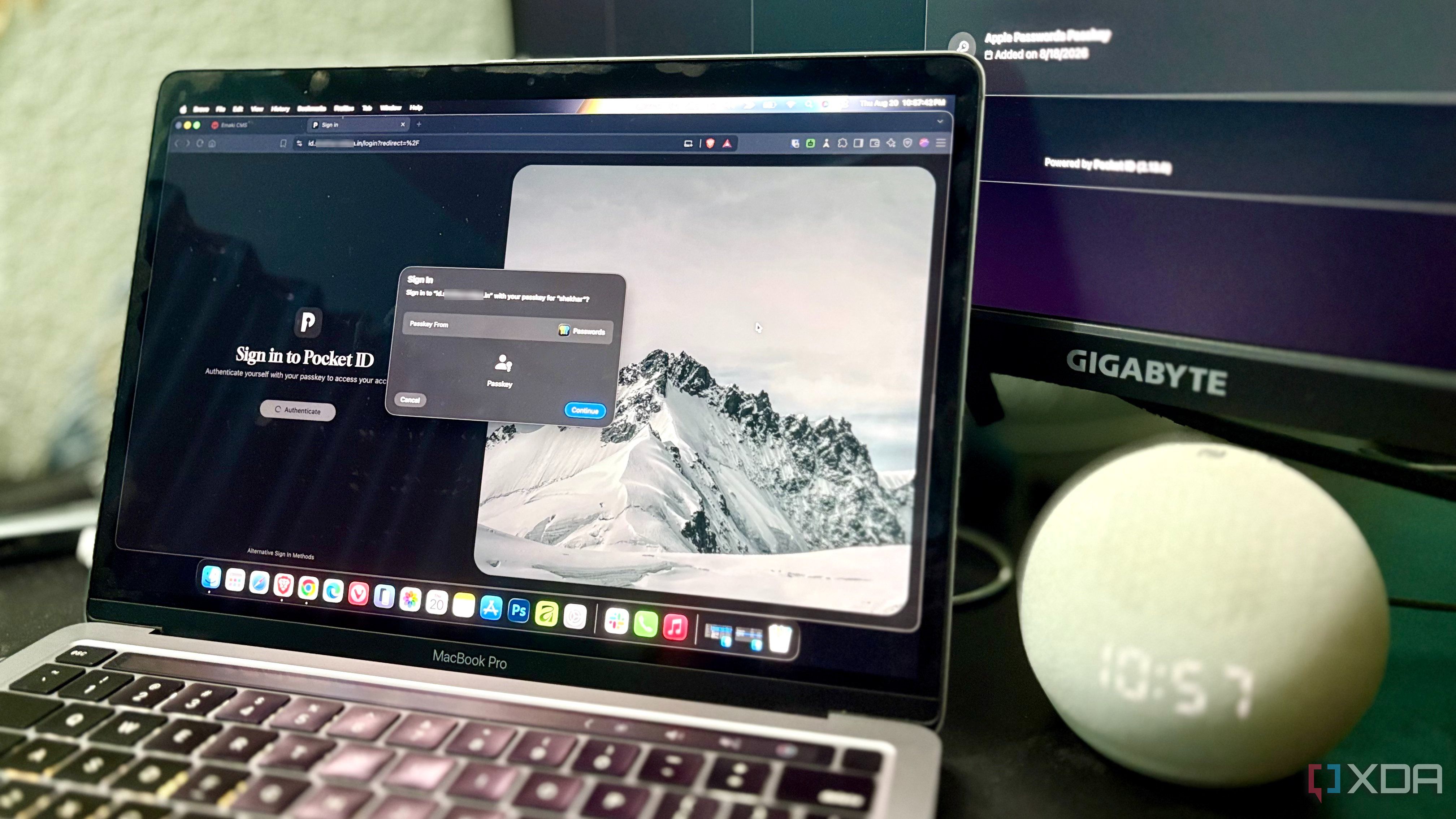 A MacBook showing a passkey sign-in prompt for Pocket ID, with a second monitor in the background displaying the account's registered passkeys