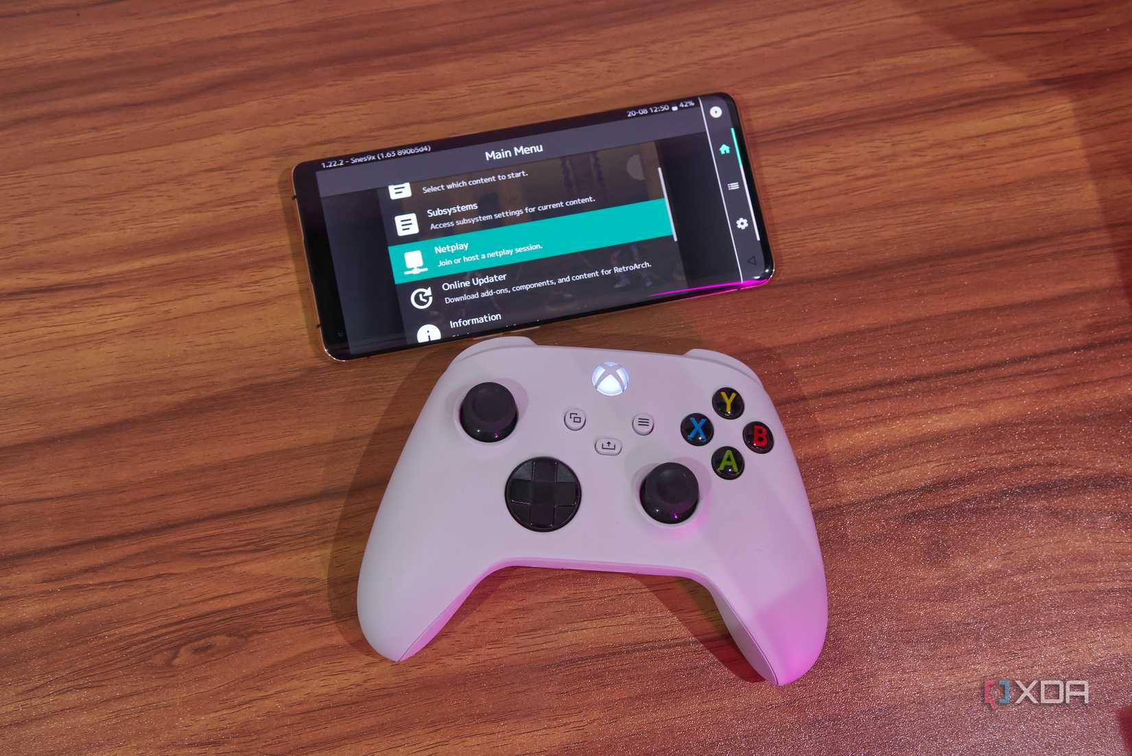 An Android phone running RetroArch and showing the Netplay option, with an Xbox controller below it