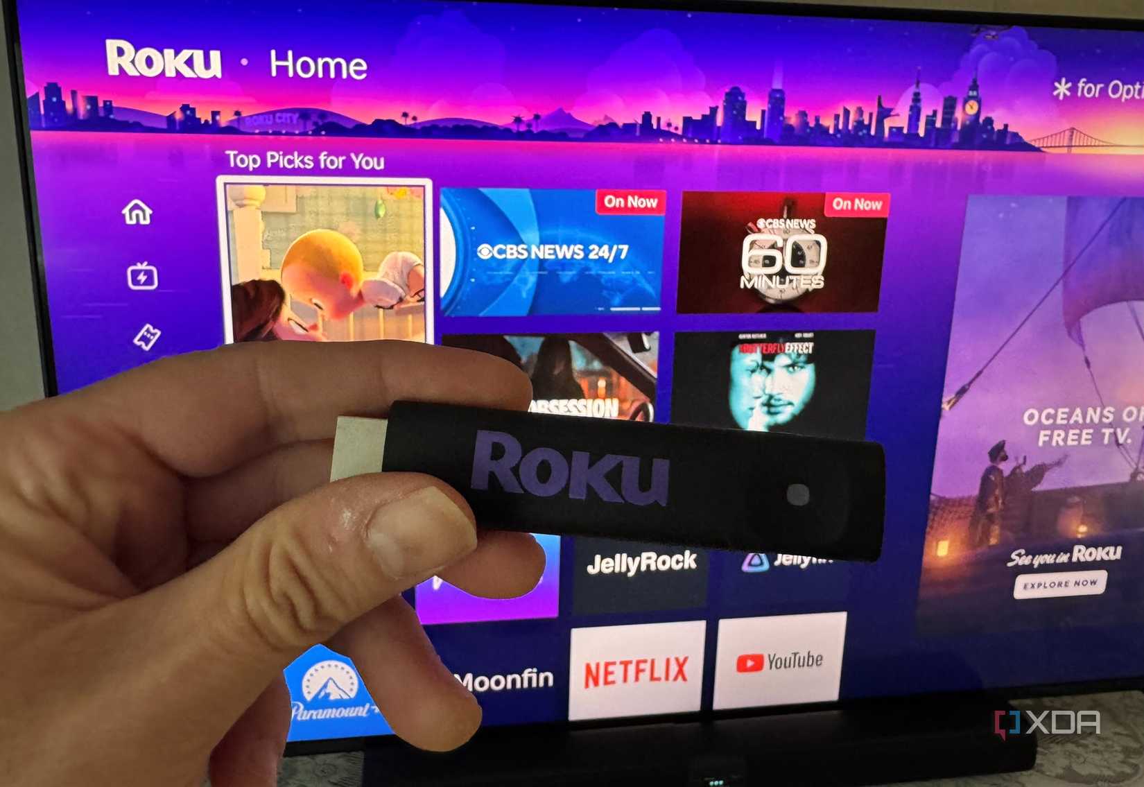 Стик Roku перед экраном с интерфейсом