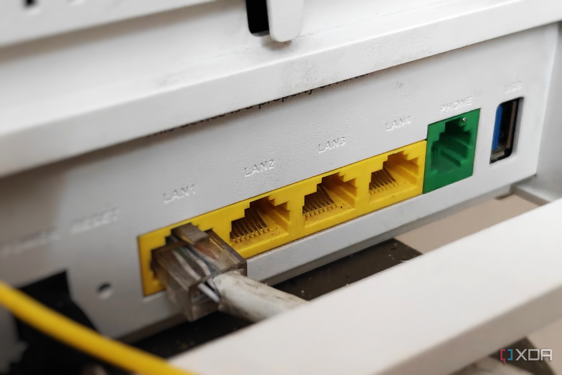 Close-up of a white router showing yellow-colored Ethernet ports with a cable plugged in