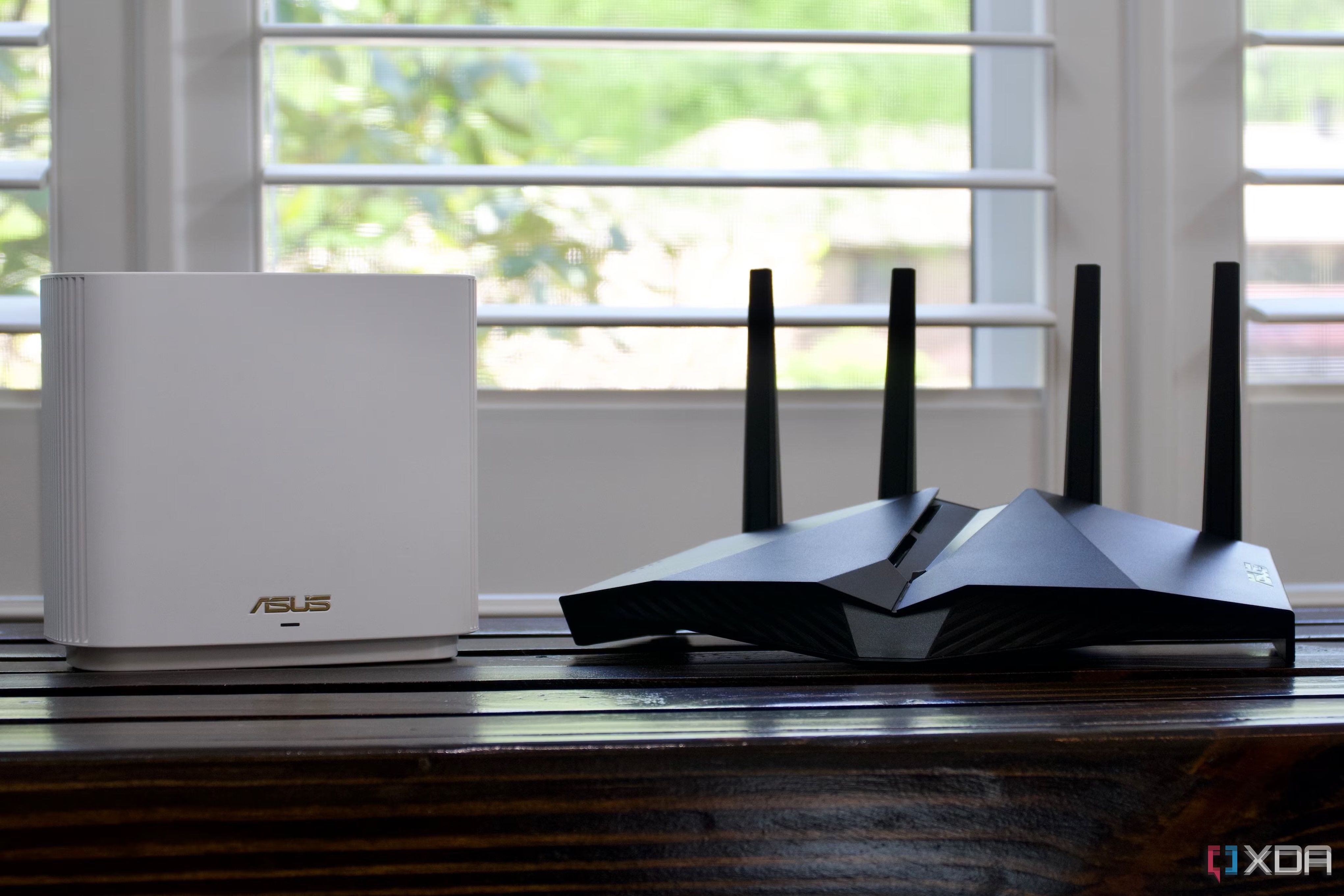 a plain white router with no visible antenna placed alongside a big gaming router