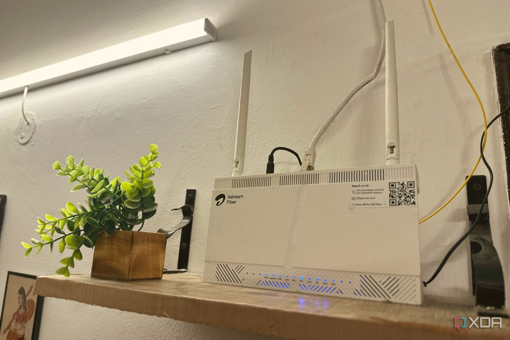 Wi-Fi router on top of a wall-mounted wooden shelf.