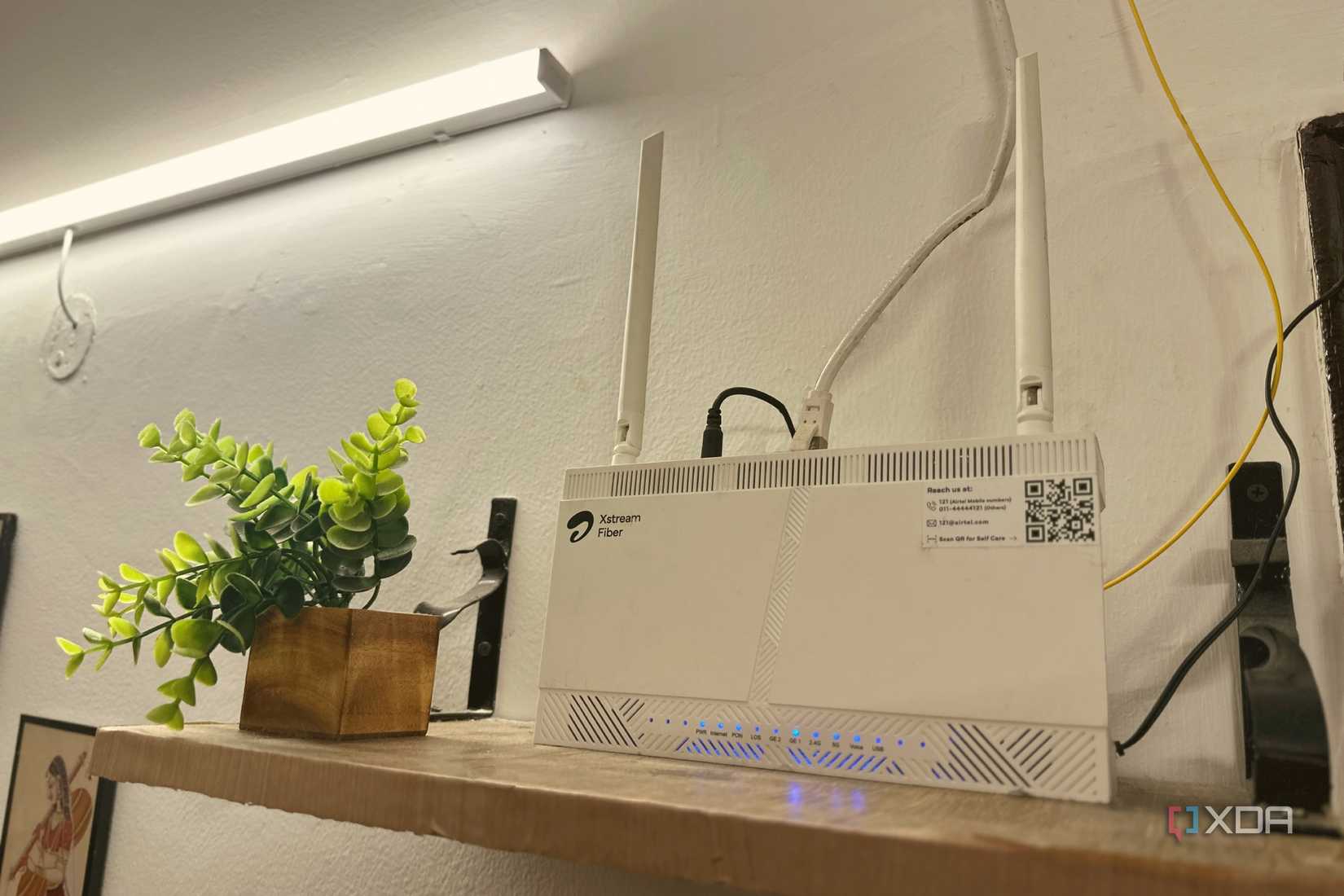 Wi-Fi router on top of a wall-mounted wooden shelf.