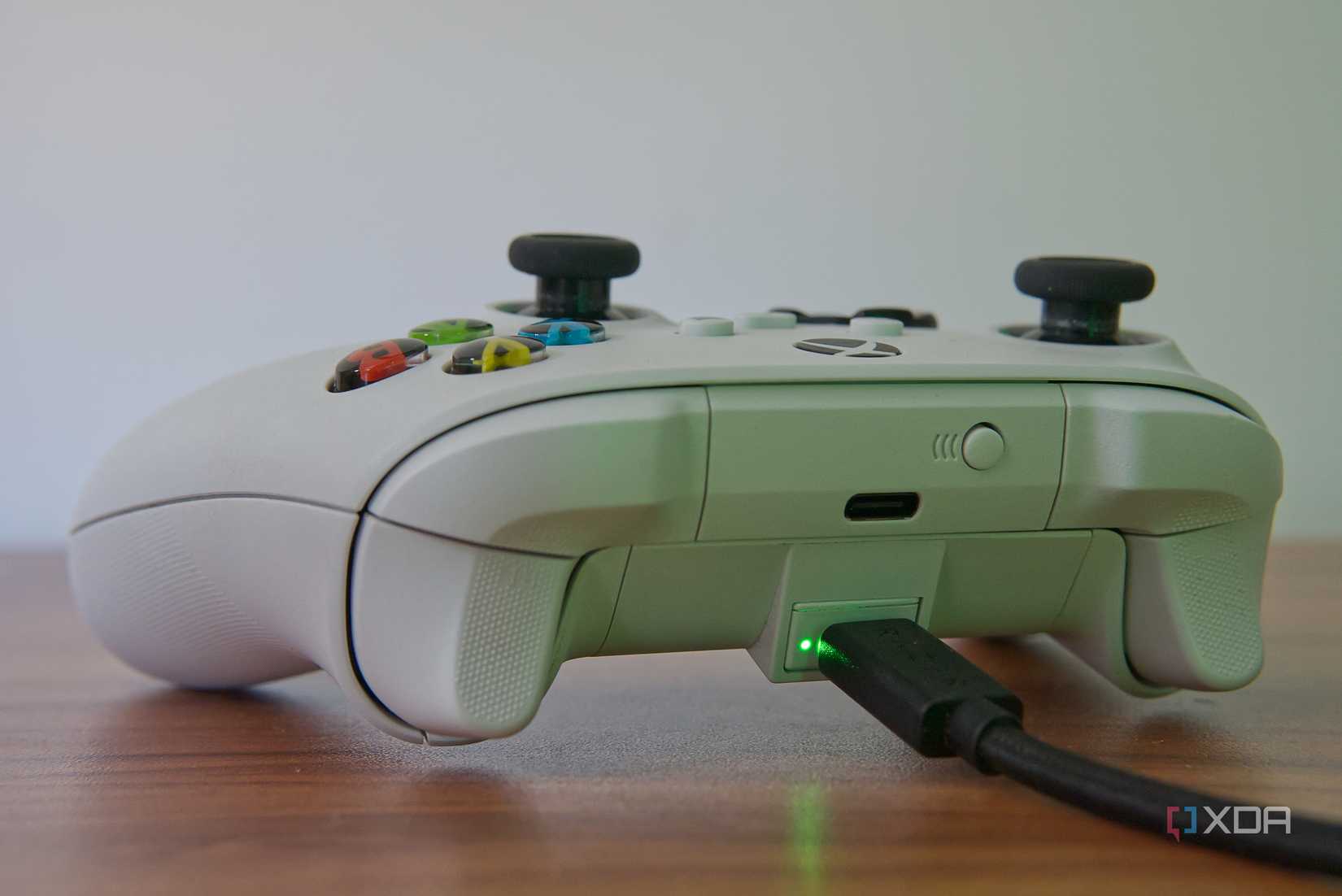 An Xbox Wireless Controller with a play and charge battery, which is connected to a charging cable. The charging indicator lightis on, indicating the charger is working