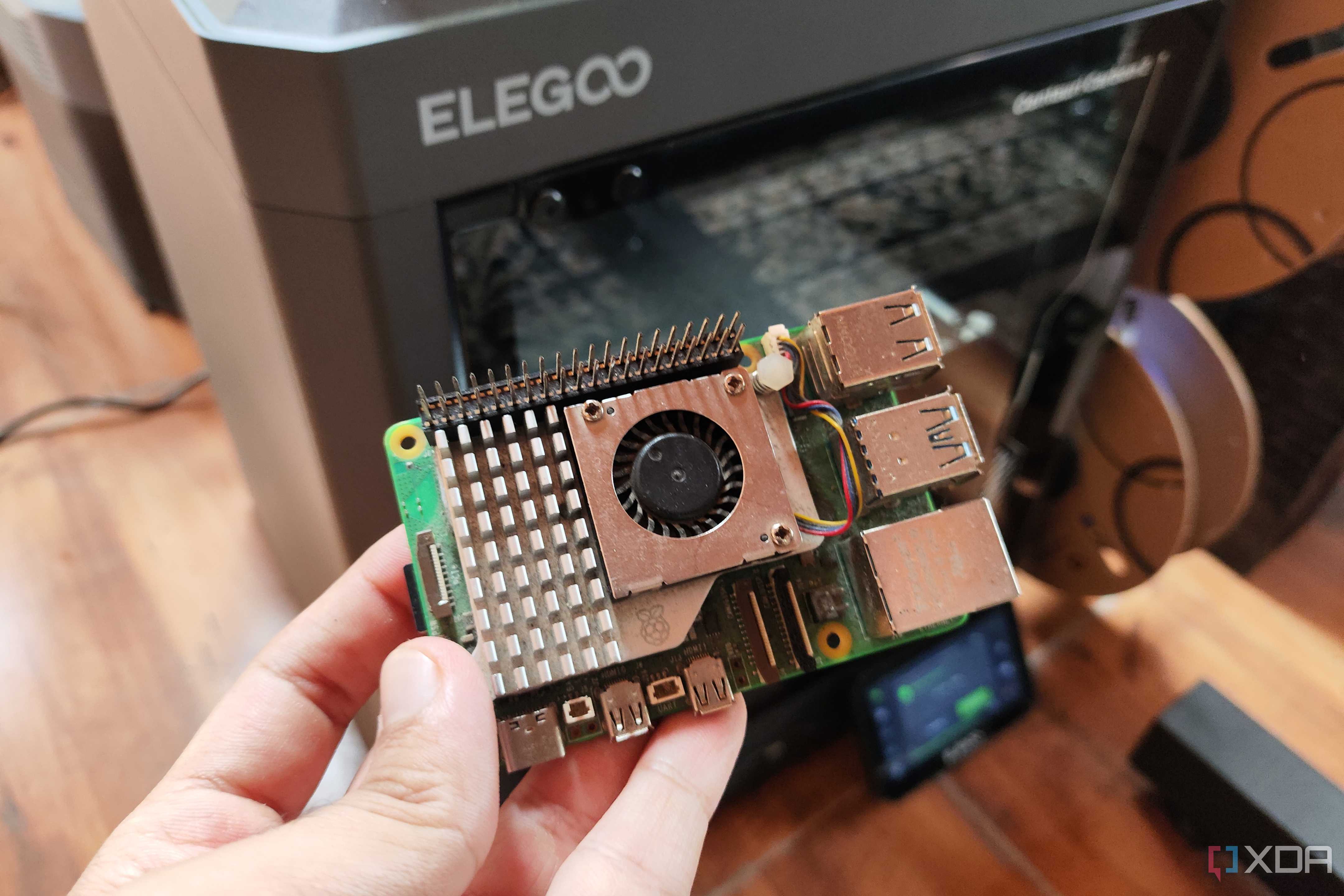 A person holding a Raspberry Pi in front of a 3D printer