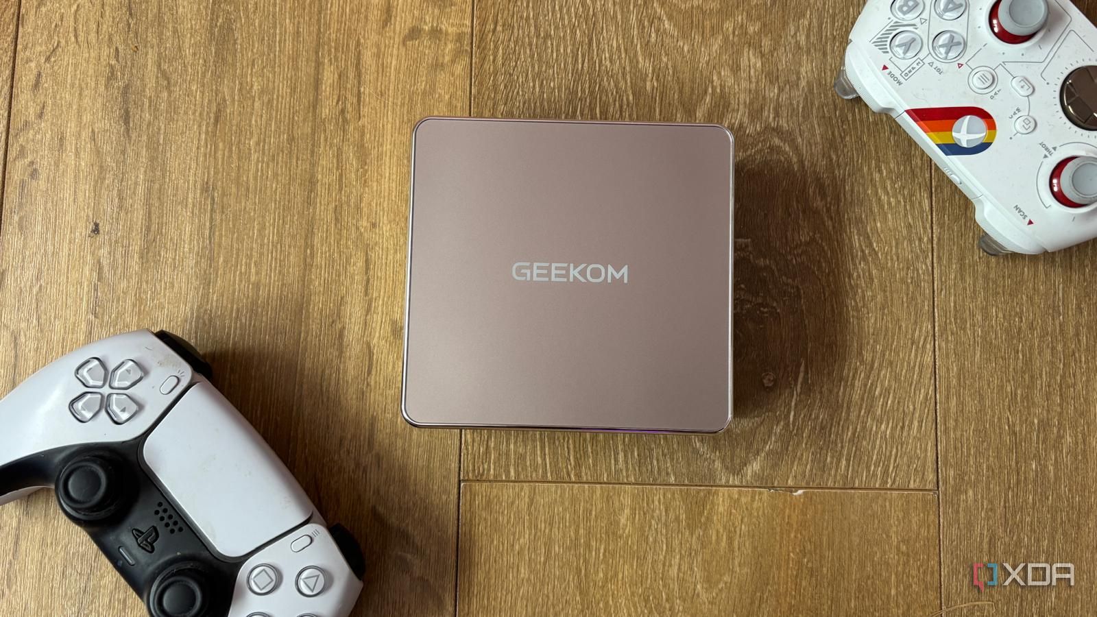 Geekom A5 2027 Mini PC on the floor with PS5 and Xbox controllers alongside