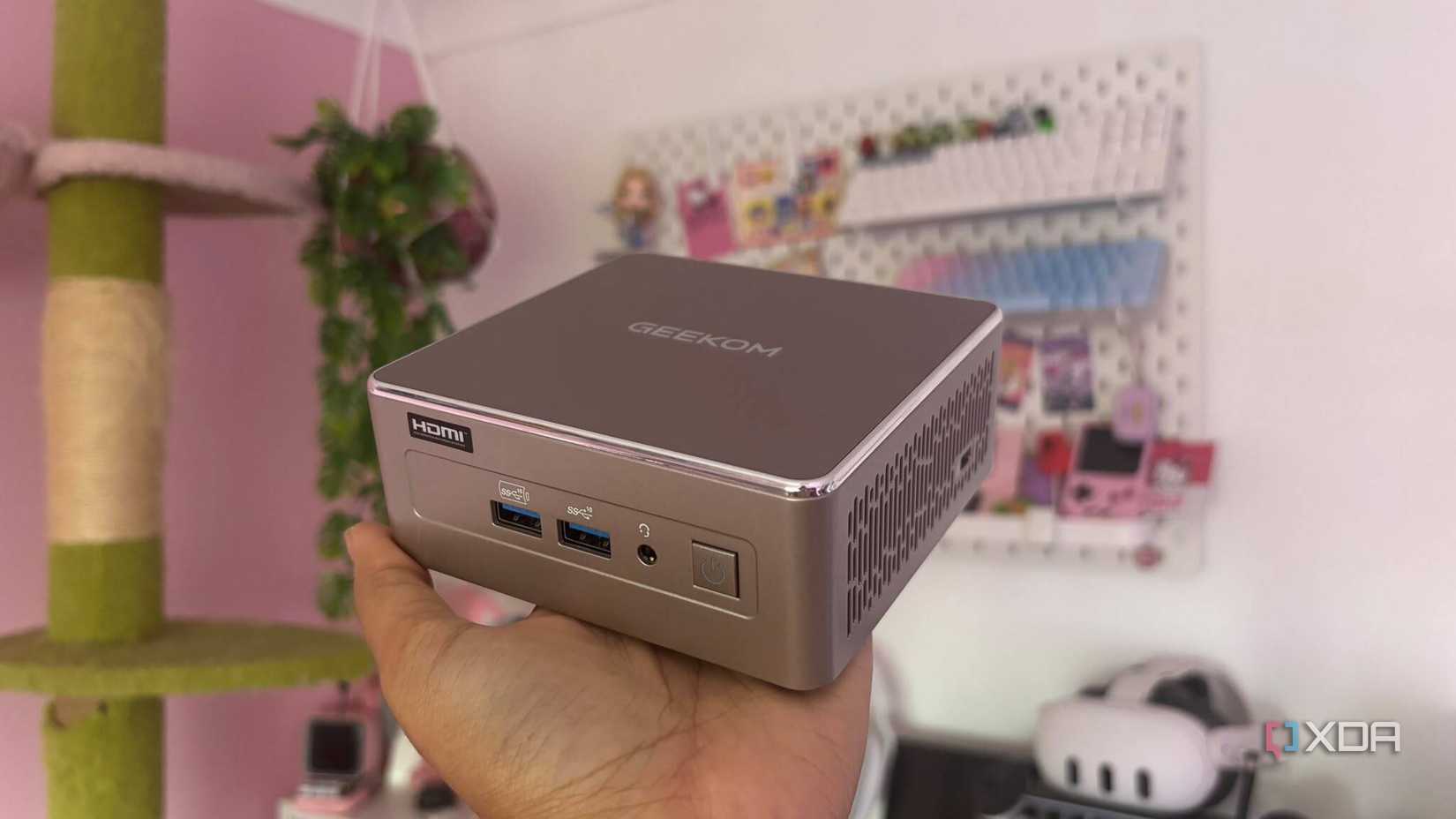 GEEKOM A5 mini PC held in hand, showing its HDMI port, USB ports, and power button