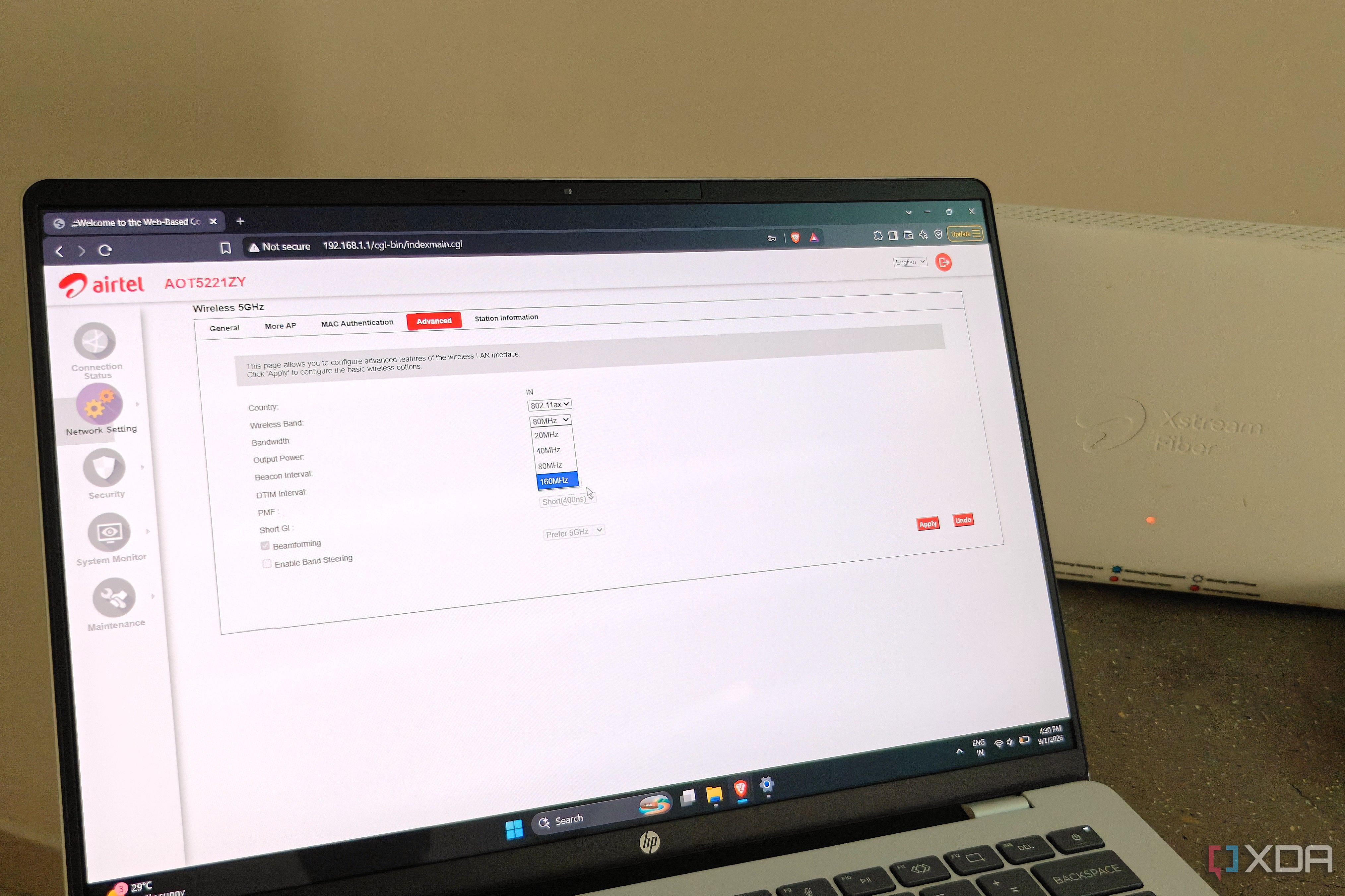 A laptop showing router settings next to a white Wi-Fi router