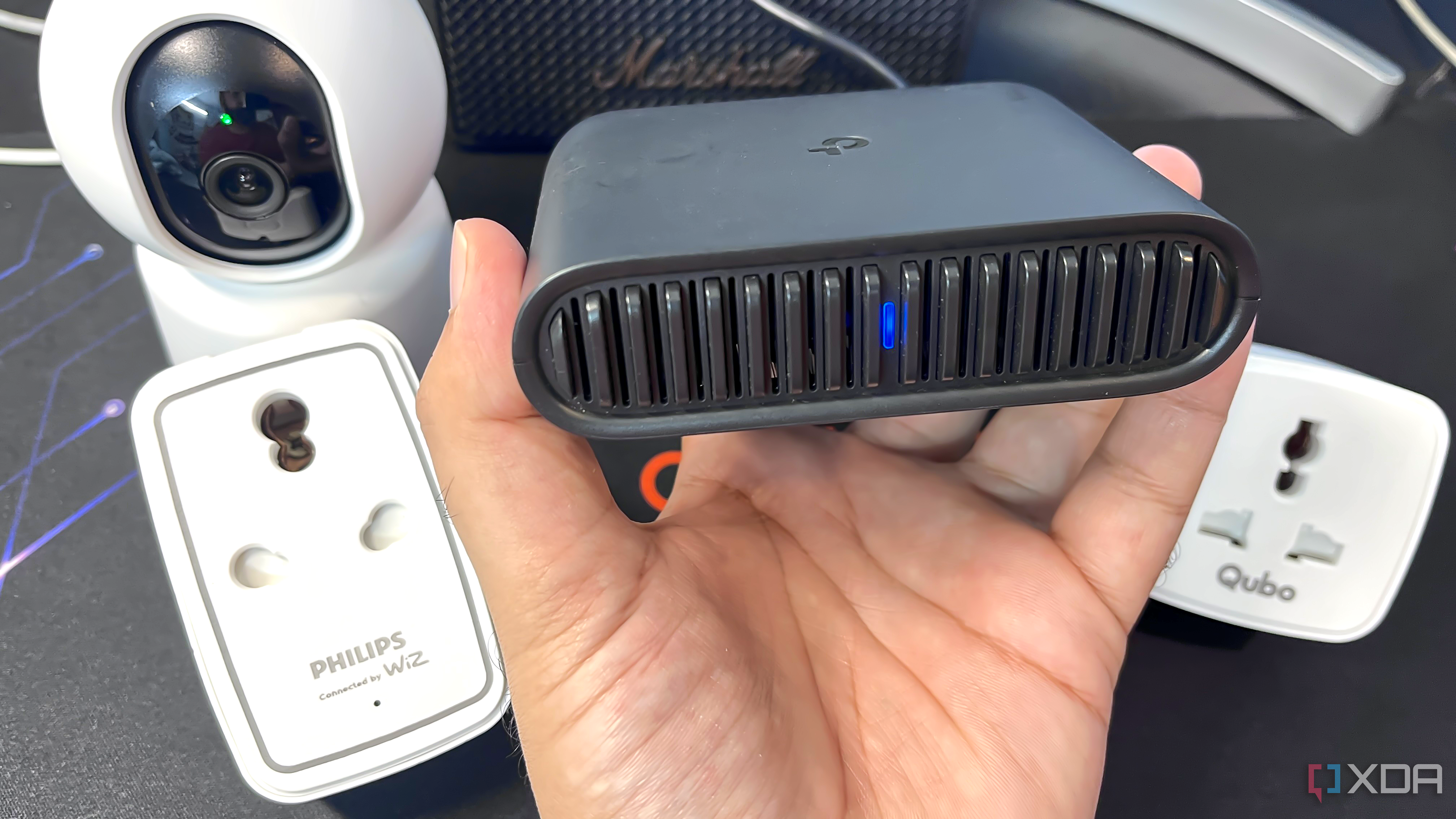 TP-Link travel router placed alongside two smart plugs, a camera, and a speaker on a table