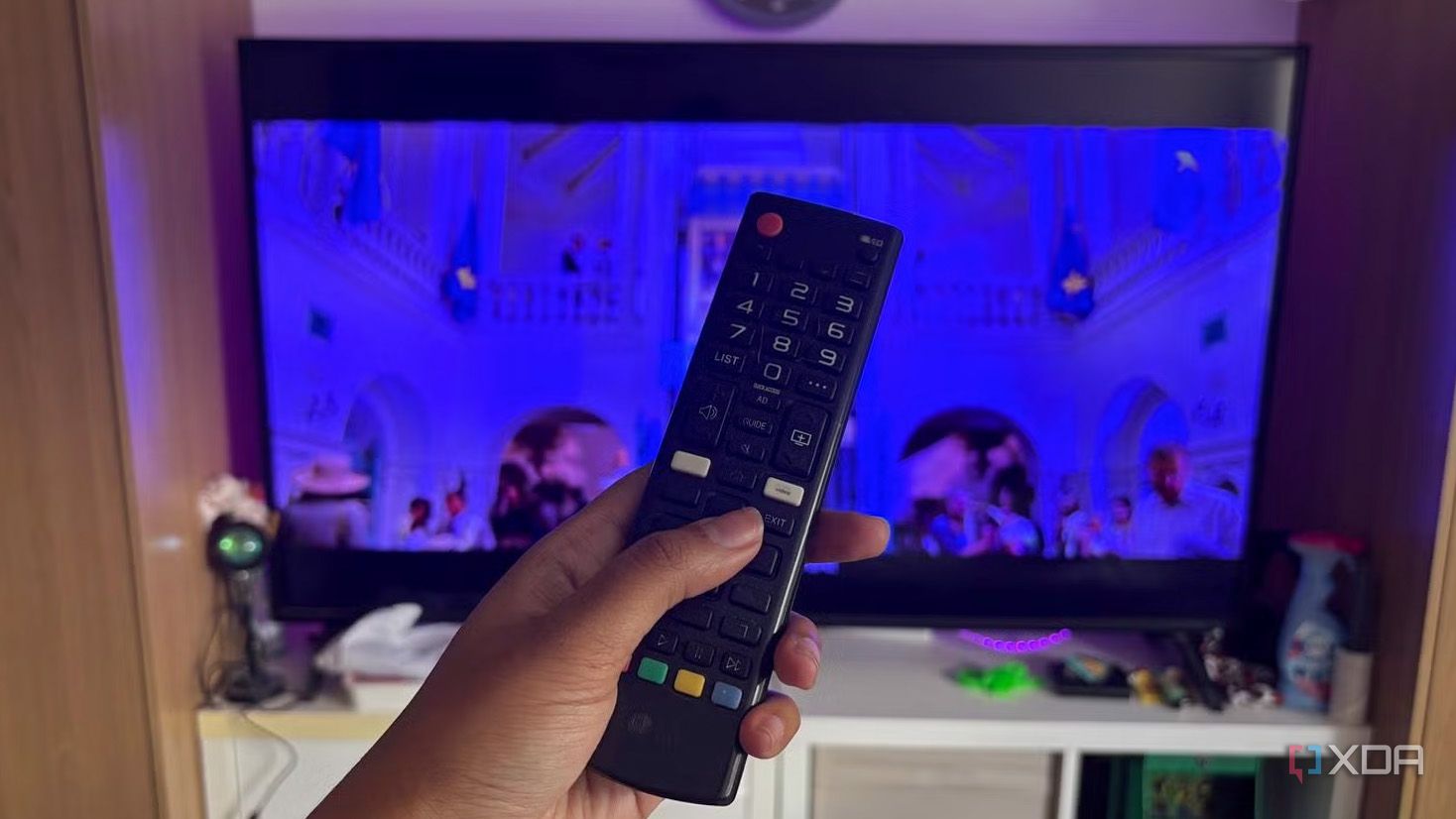 A TV remote being held up in front of TV