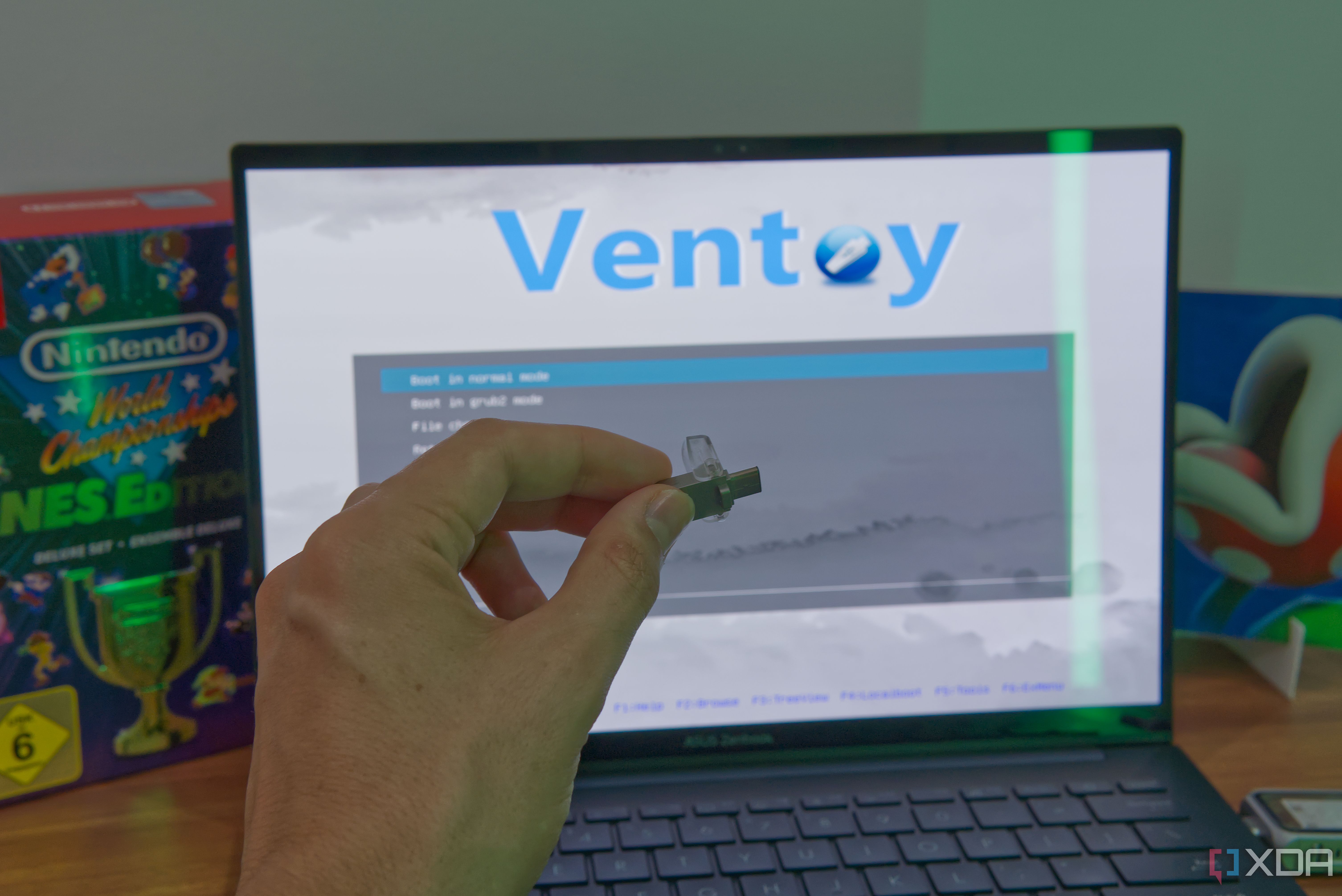 A flash drive in front of a laptop diosplaying the Ventoy menu