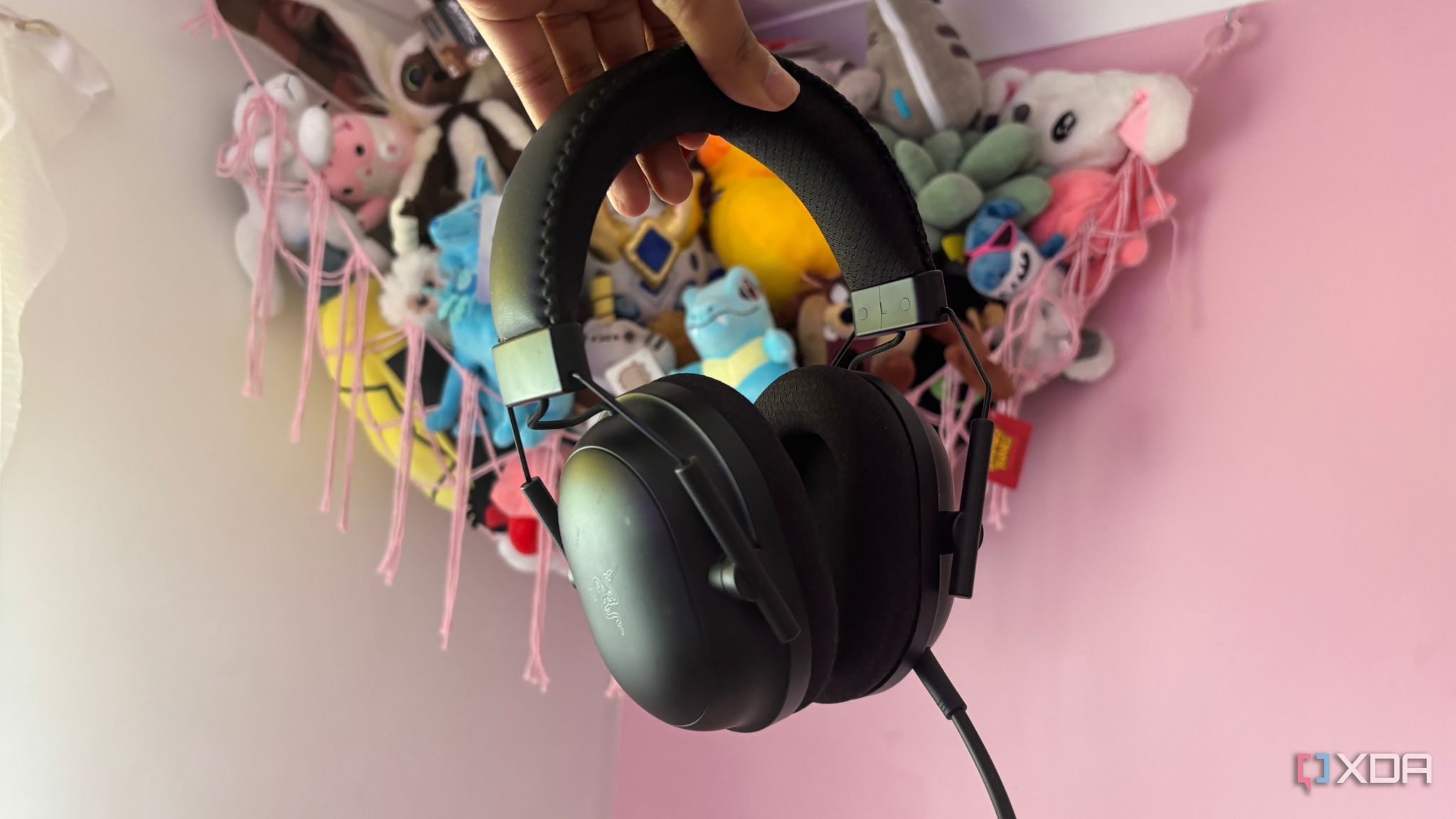 gaming headset being held up and shown on pink background