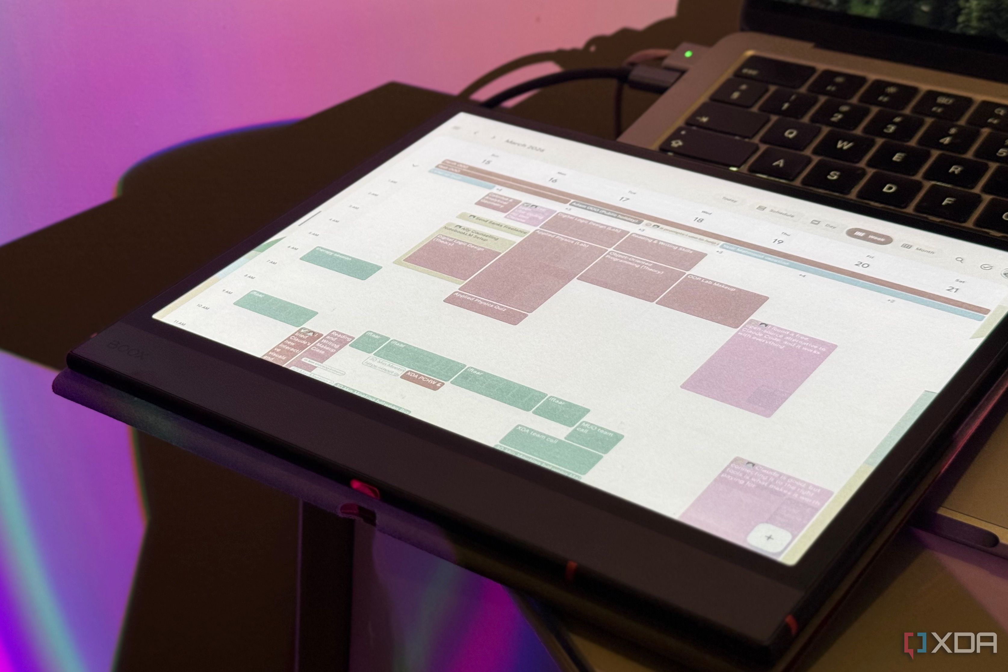 Boox tablet in a folio case showing Google Calendar in front of a MacBook keyboard