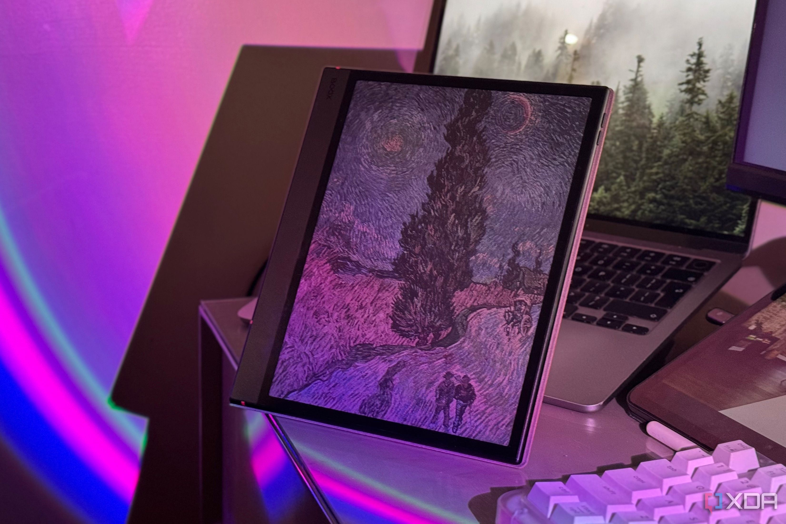 Boox tablet with a Van Gogh painting on screen beside a MacBook and a white keyboard