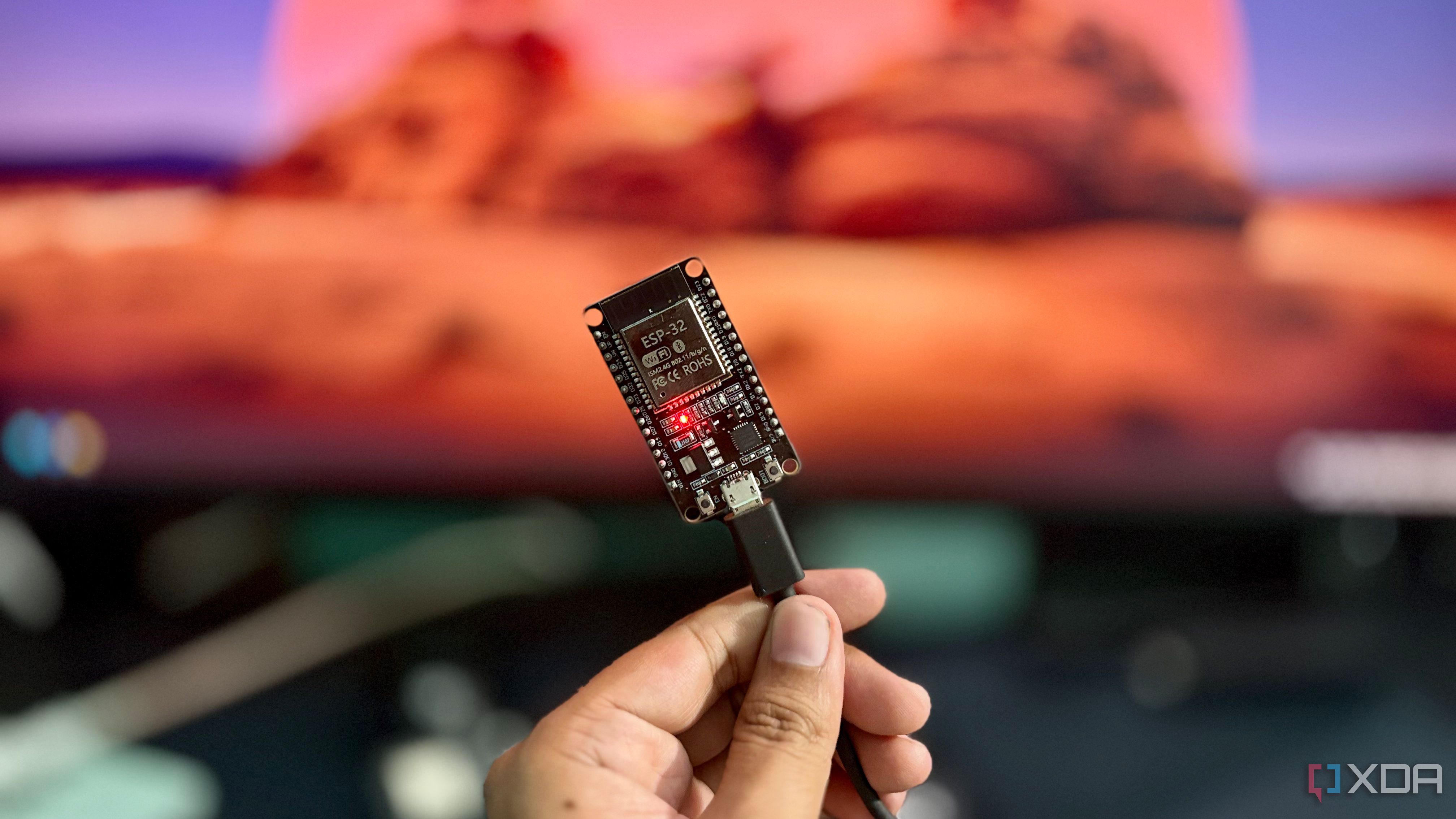 ESP32 NodeMCU development board held in hand with a USB cable plugged in