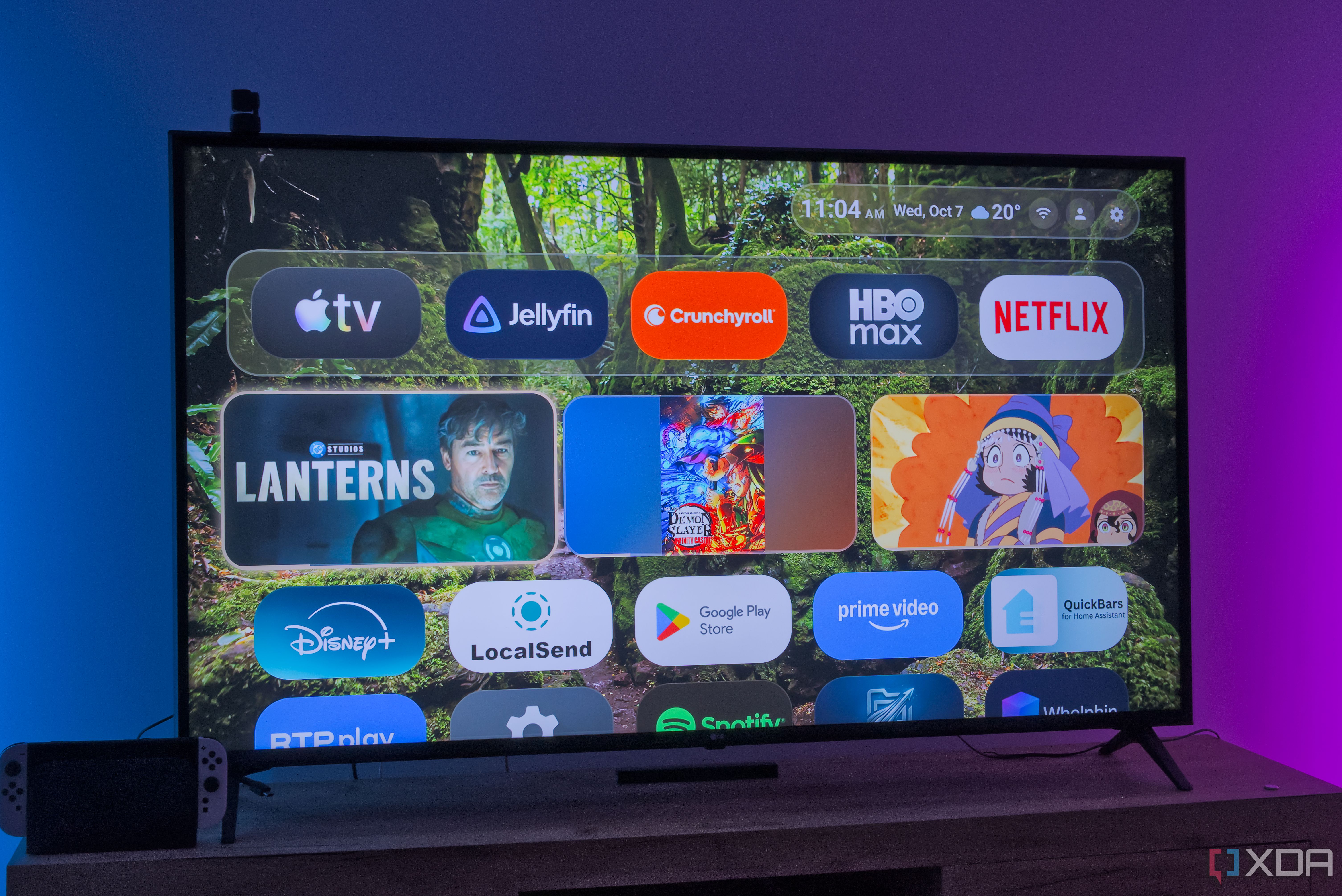 A TV displaying the home screen in Monet launcher, with a row of pinned apps at the top, followed by a row of recently watched content, and then a list of all apps 