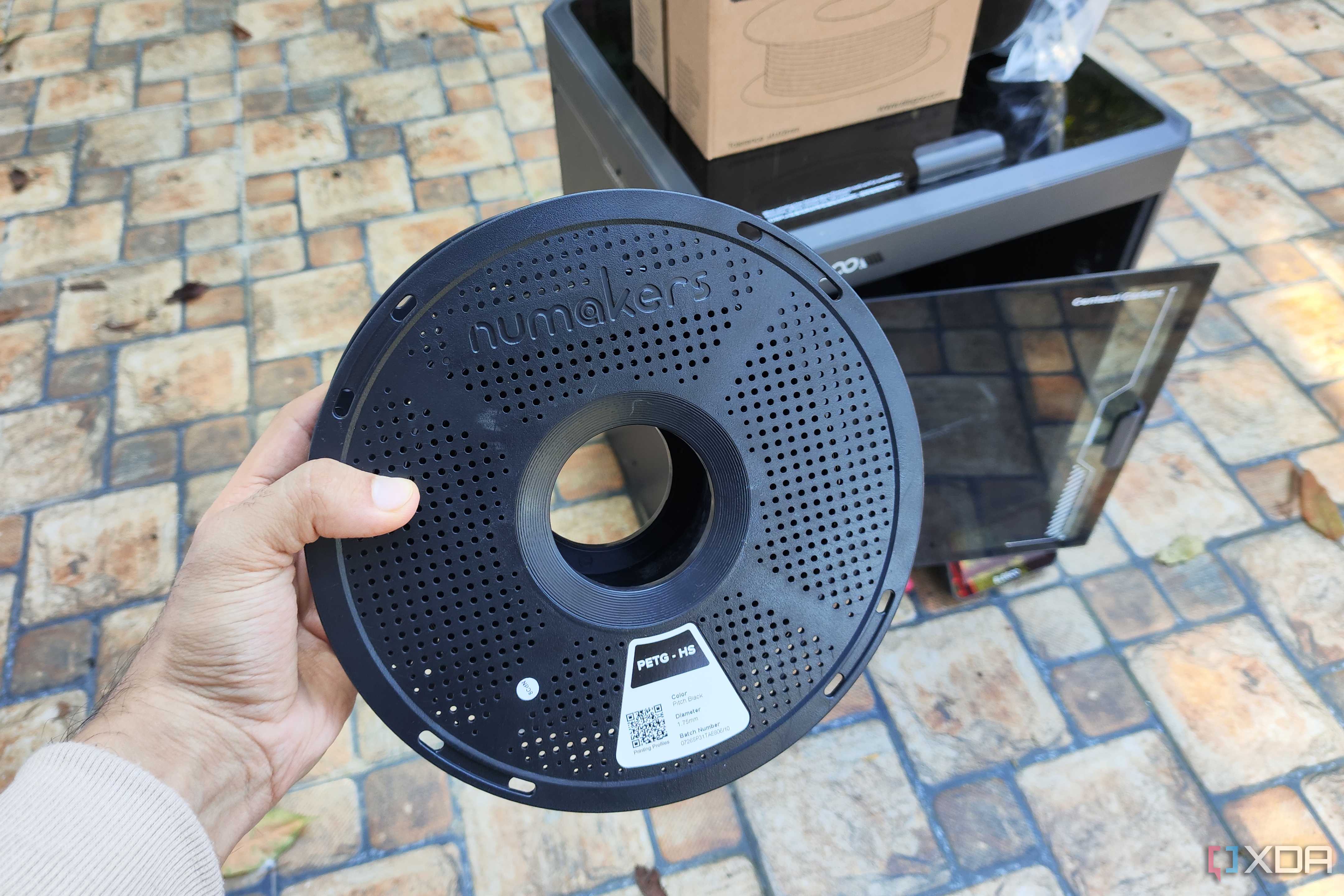 A person holding a PETG spool