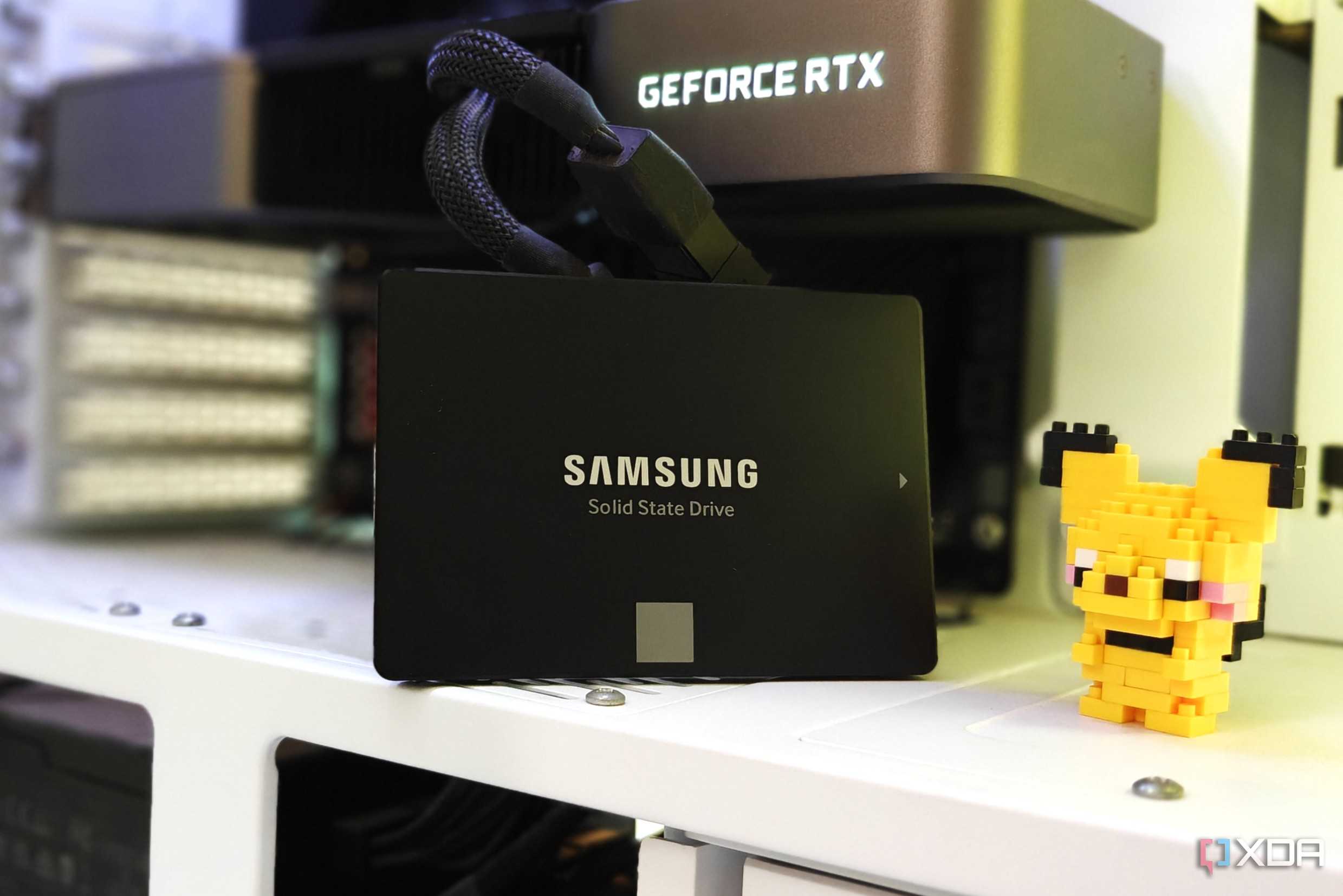 A black SATA SSD inside a gaming PC next to a GPU and a figurine
