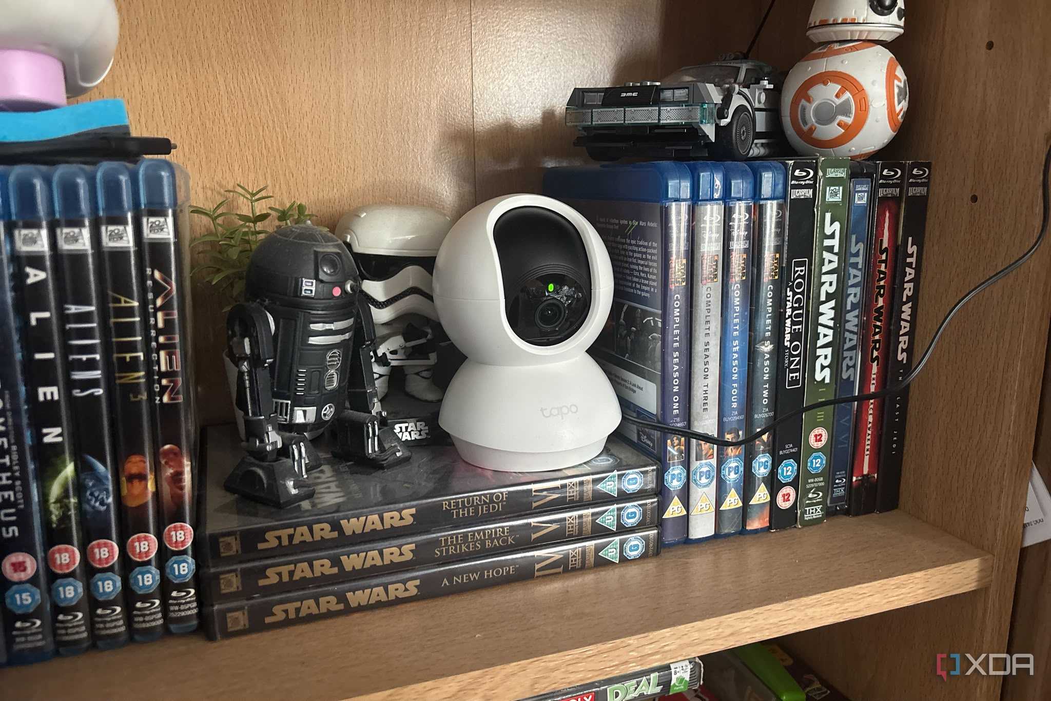 tapo camera on shelf next to figures and blu rays