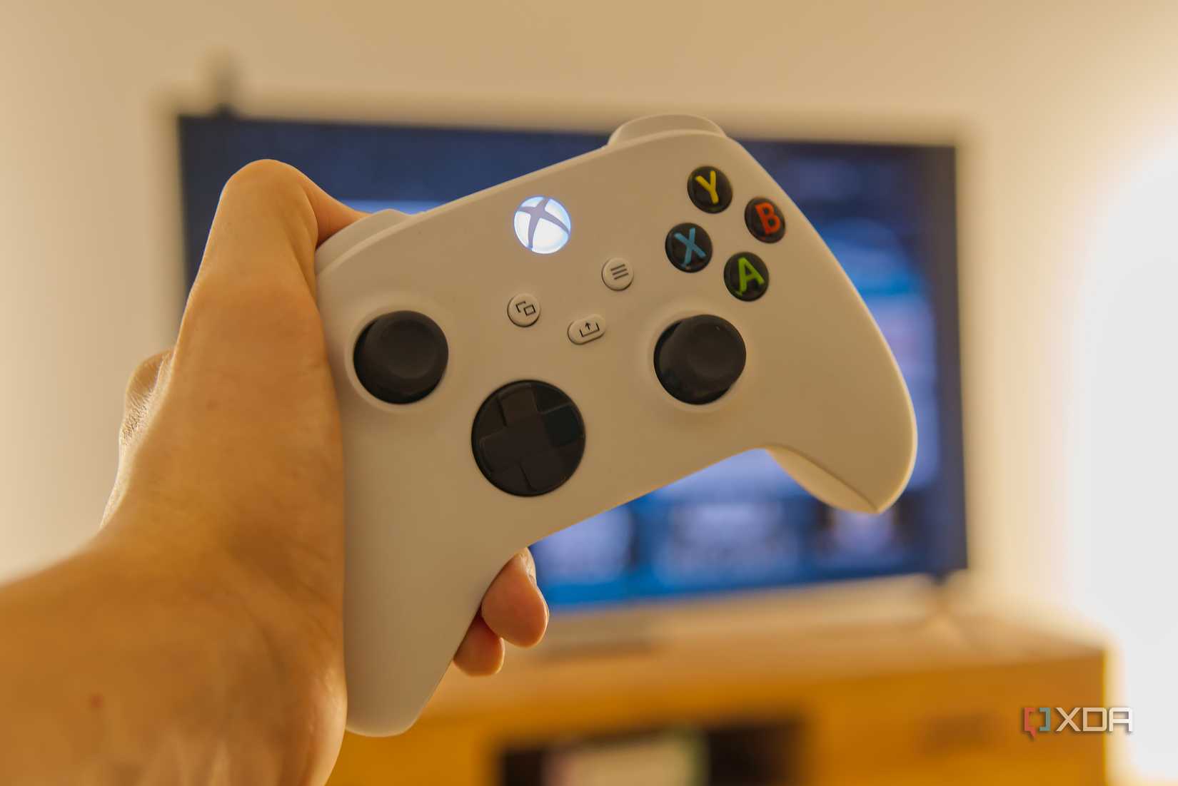 An Xbox Wireless Controller held in front of a TV